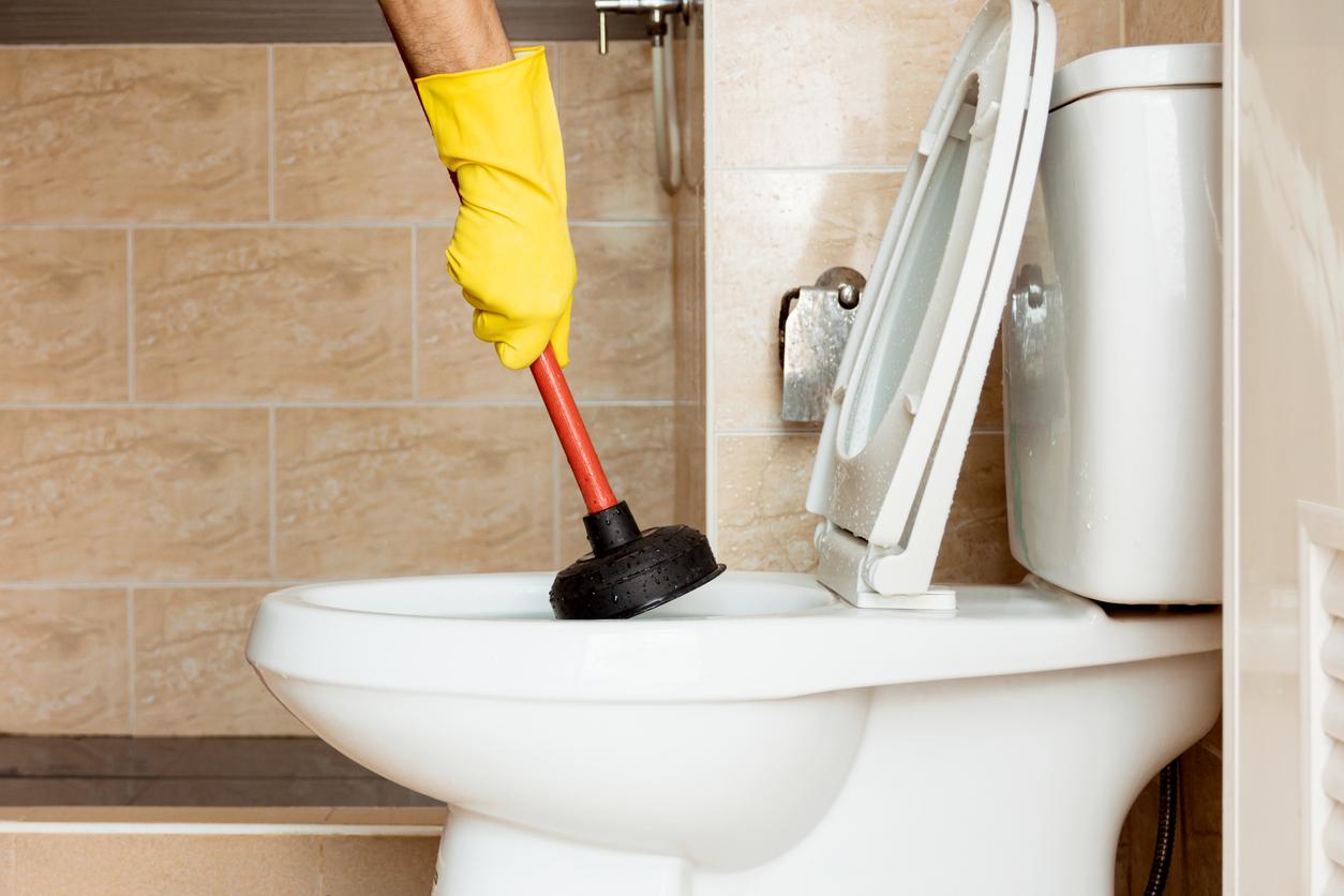 Plumber using a plunger to fix a clogged toilet