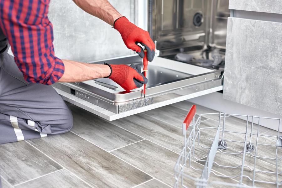 Plumber installing or repairing a kitchen dishwasher